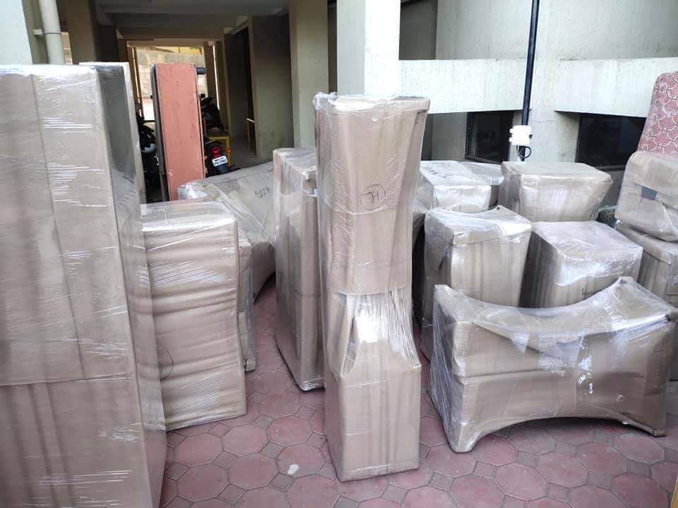 Wrapped furniture and household items grouped near building access for loading